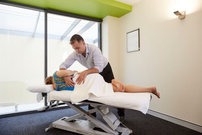 a photo of our osteopath george asproukos examining a patient and assisting with manage injuries